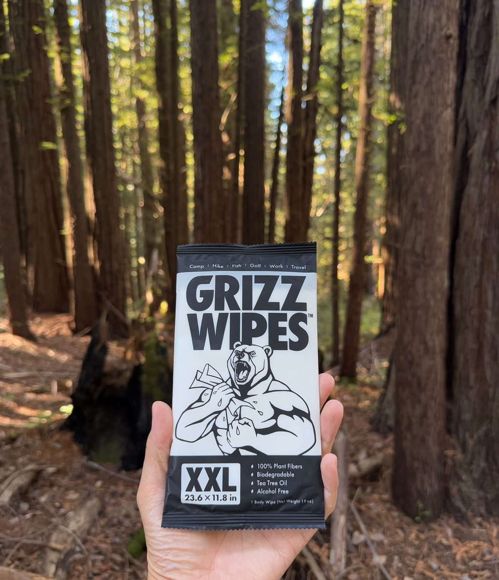 A picture of an individual satchet of Grizz Wipes set against a wooded background.